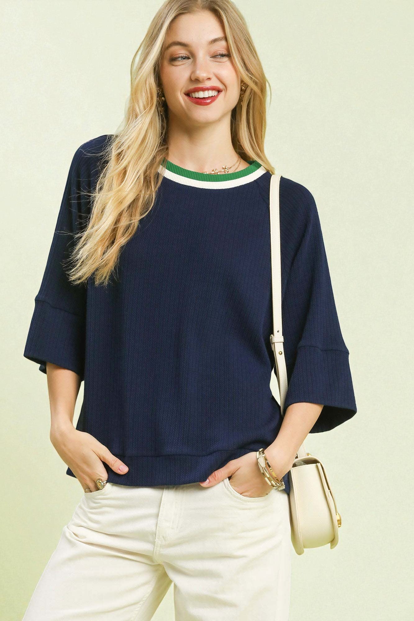 Woman wearing a navy blue sweater with green trim on a light green background