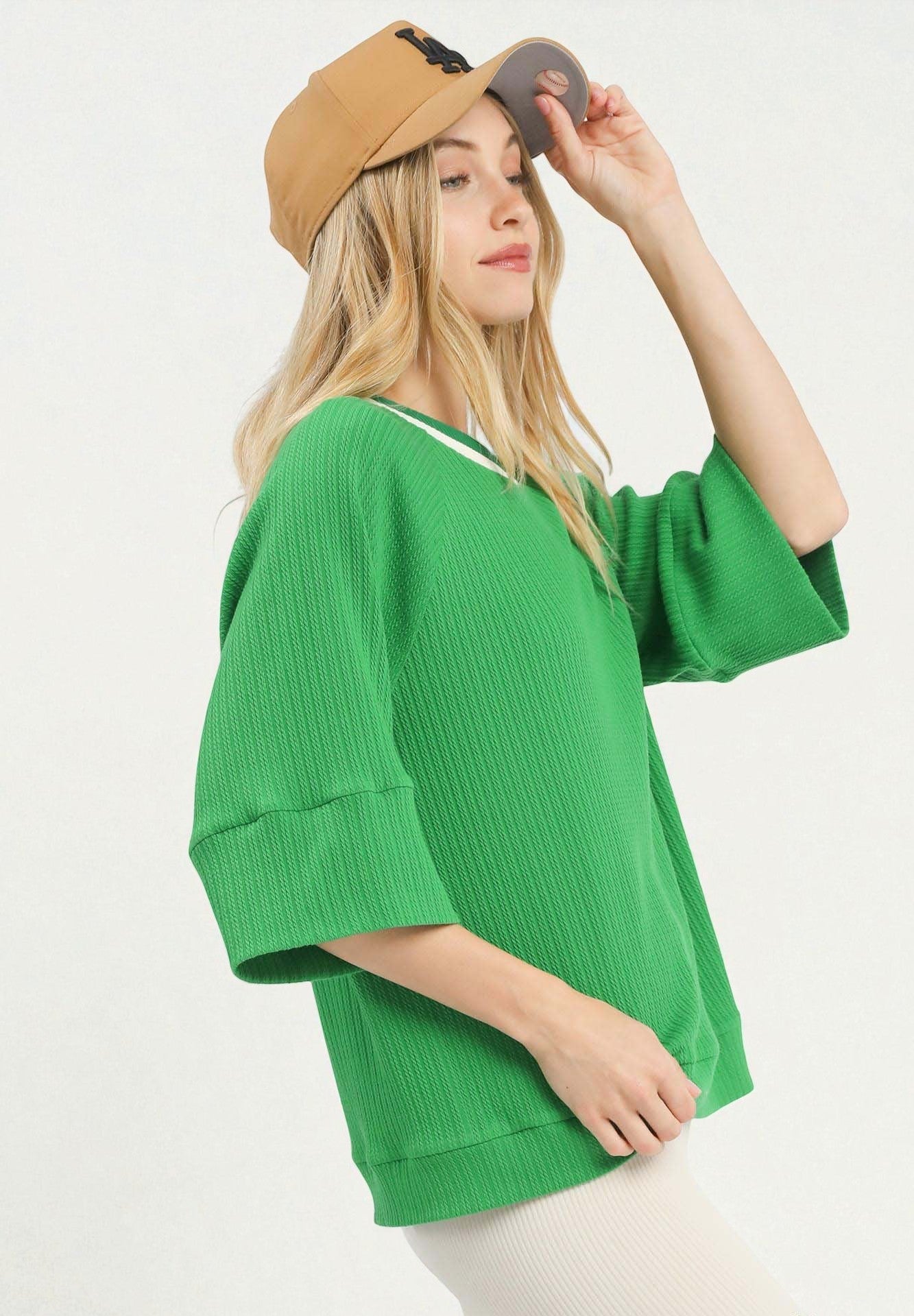 Woman wearing a green oversized sweater and beige cap on a white background