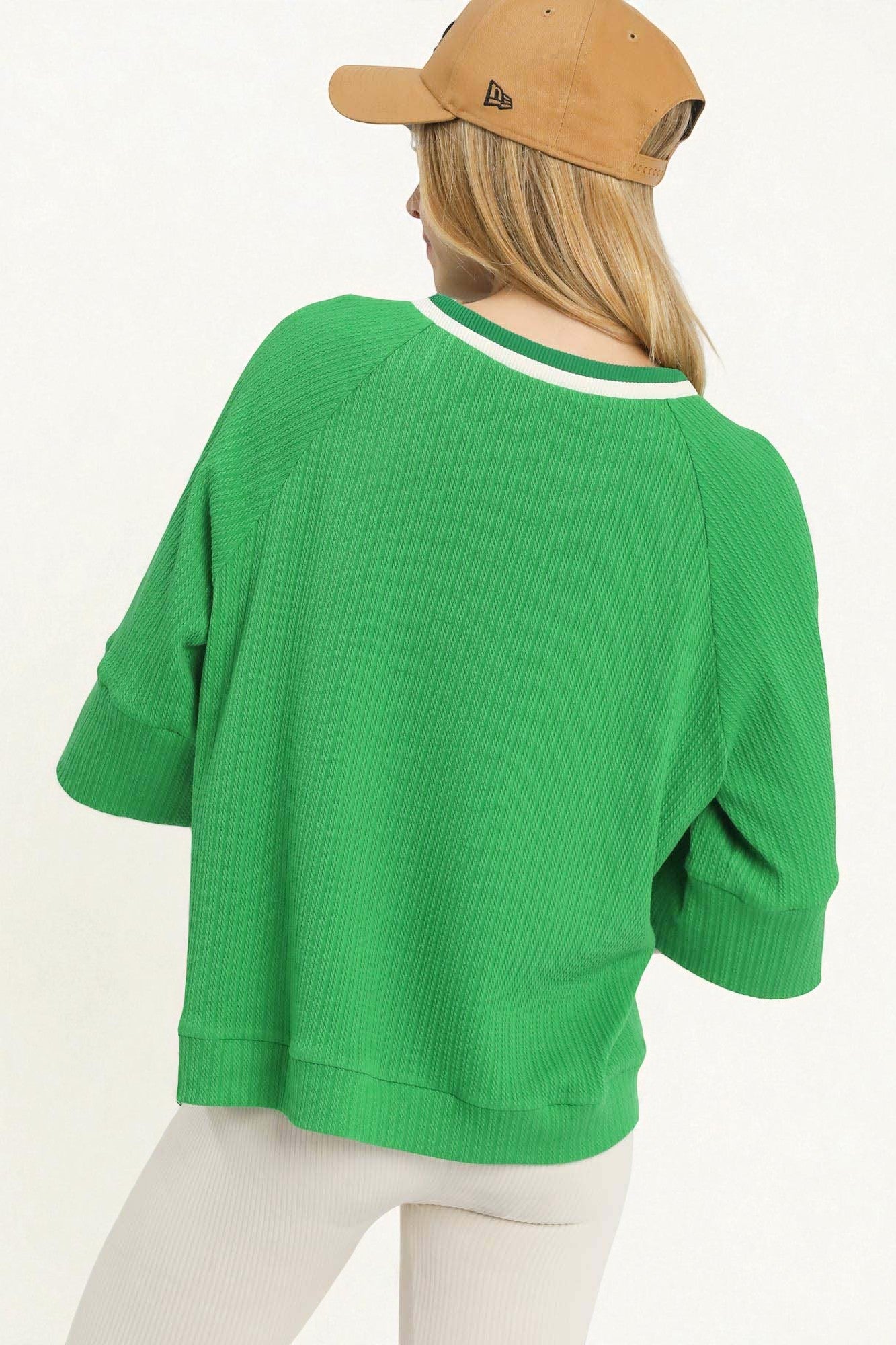 Person wearing a green sweater and beige cap on a white background