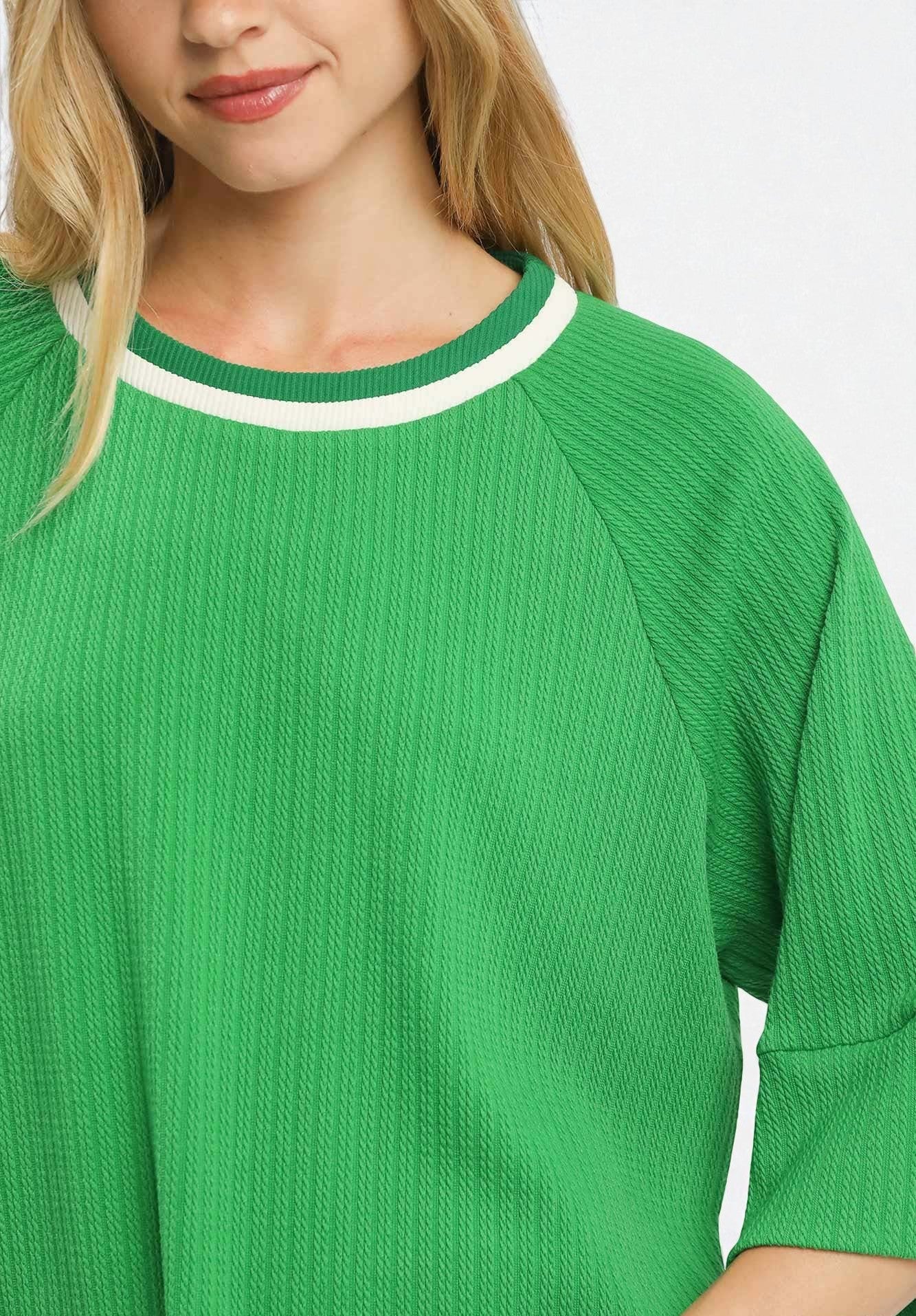 Green sweater with white trim on a plain background