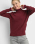 Woman wearing a burgundy sweater with pink cuffs against a white background