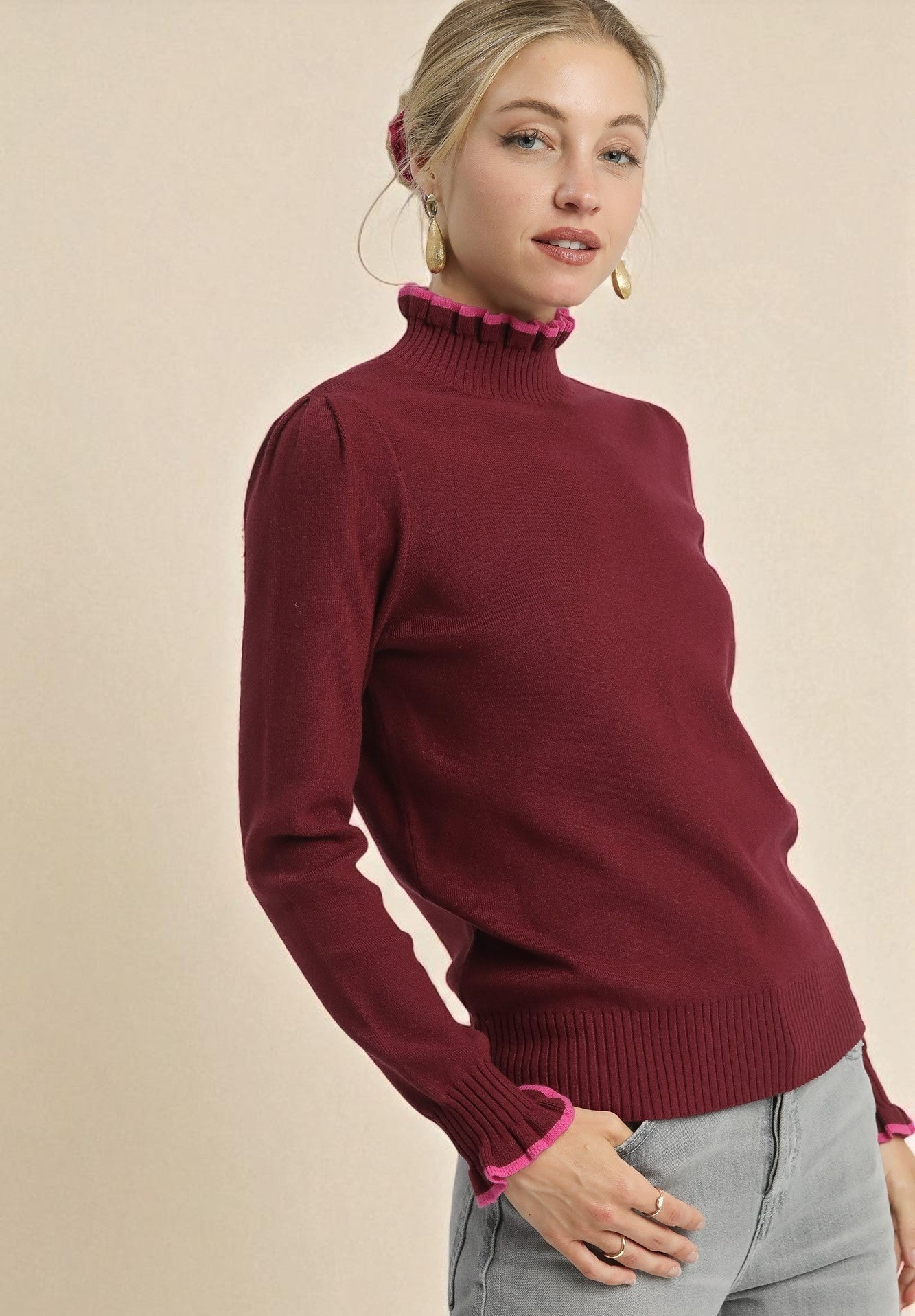 Woman wearing a burgundy sweater with a beige background