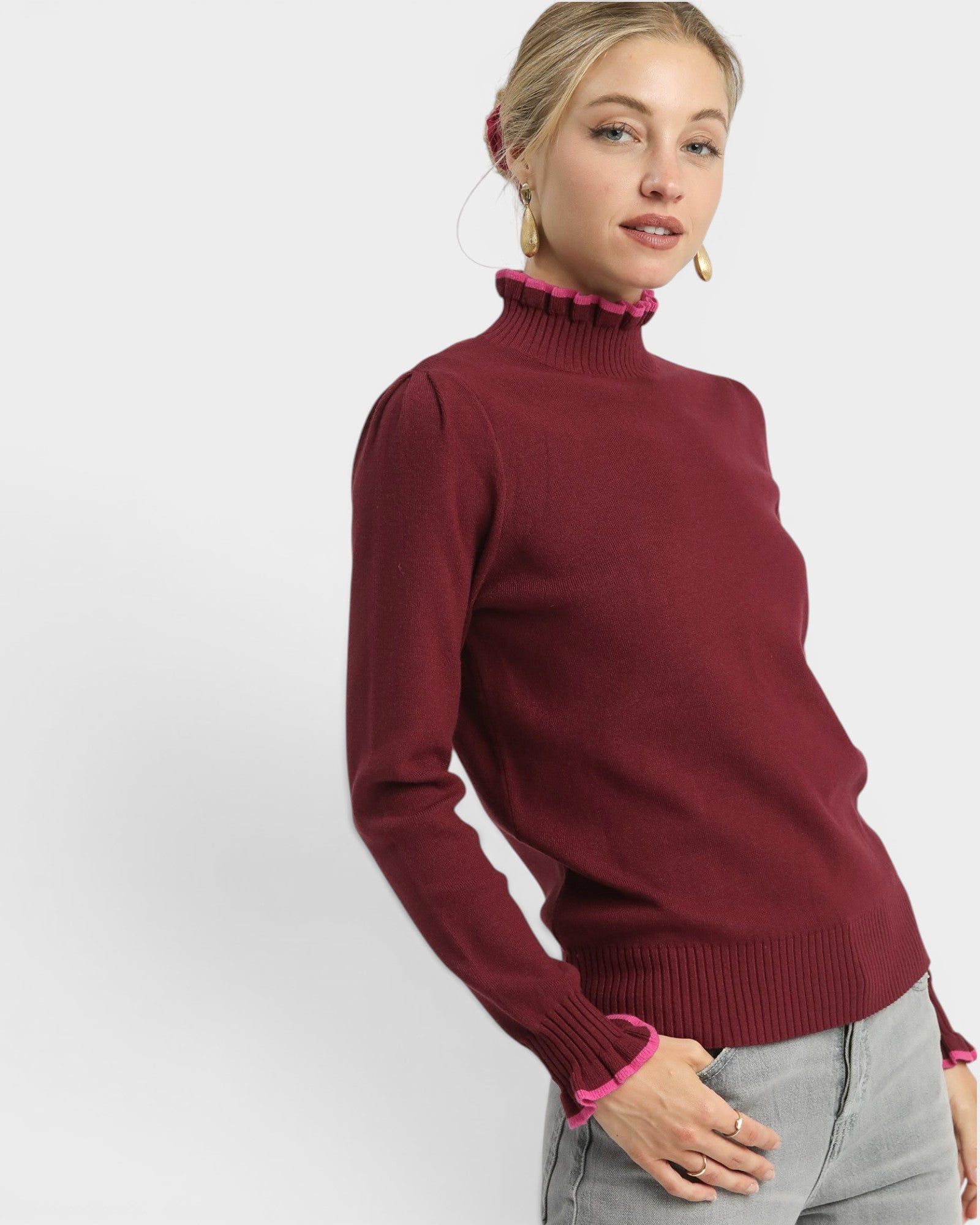 Woman wearing a burgundy sweater with pink trim on a white background