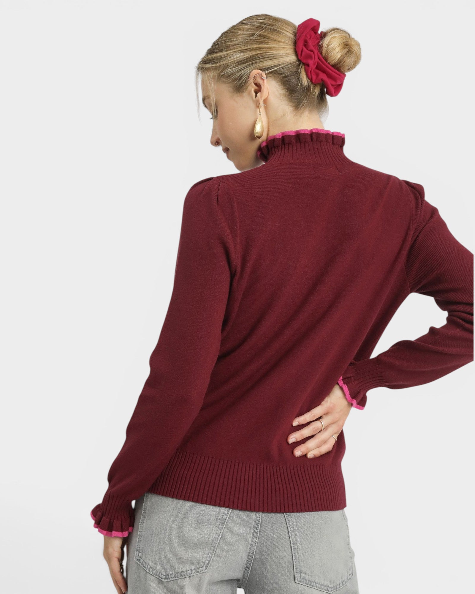 Woman wearing a burgundy sweater with a plain background