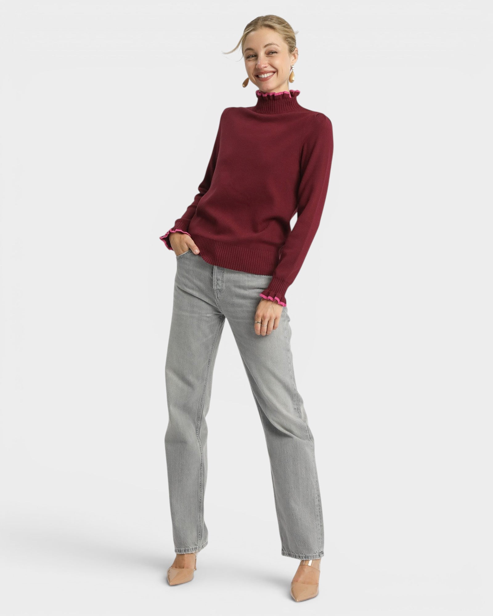 Woman wearing a burgundy sweater and gray pants on a white background