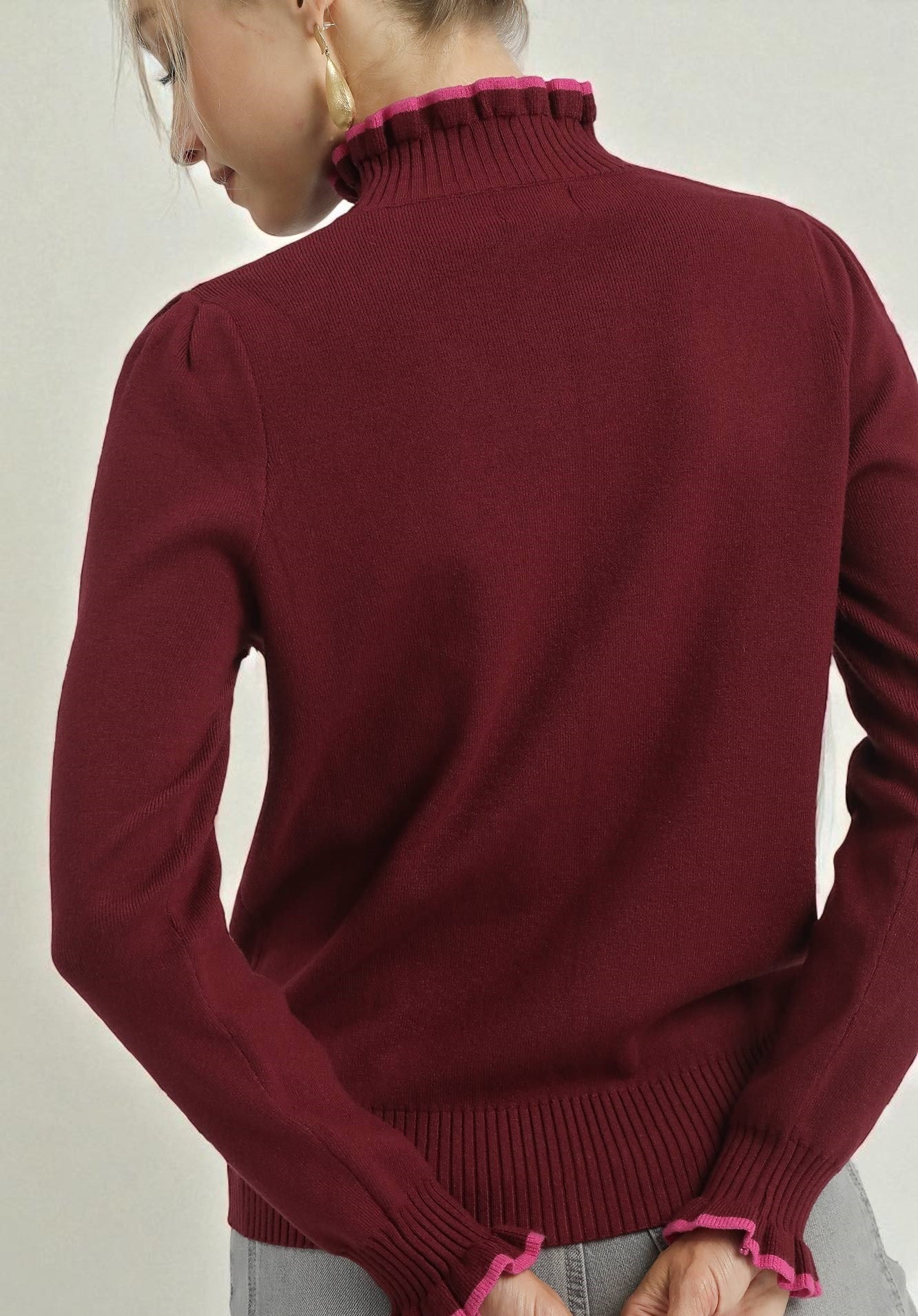 Burgundy sweater with pink trim on a plain background