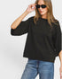 Woman wearing a black oversized sweater and blue jeans against a white background