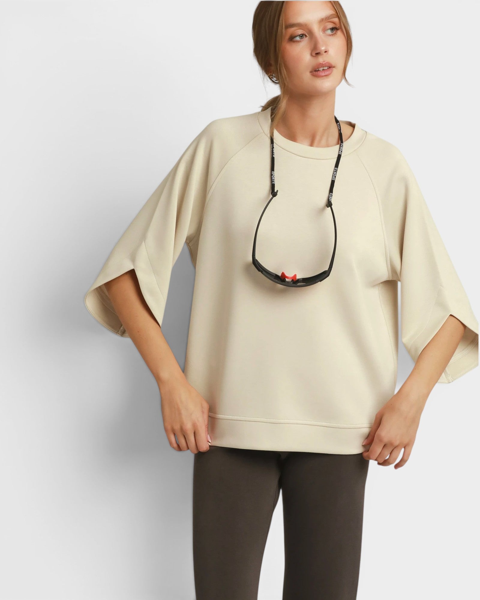 Woman wearing a beige oversized sweater with a plain background