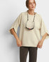 Woman wearing a beige oversized sweater with a plain background