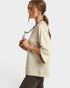 Woman wearing a beige sweater holding sunglasses on a white background