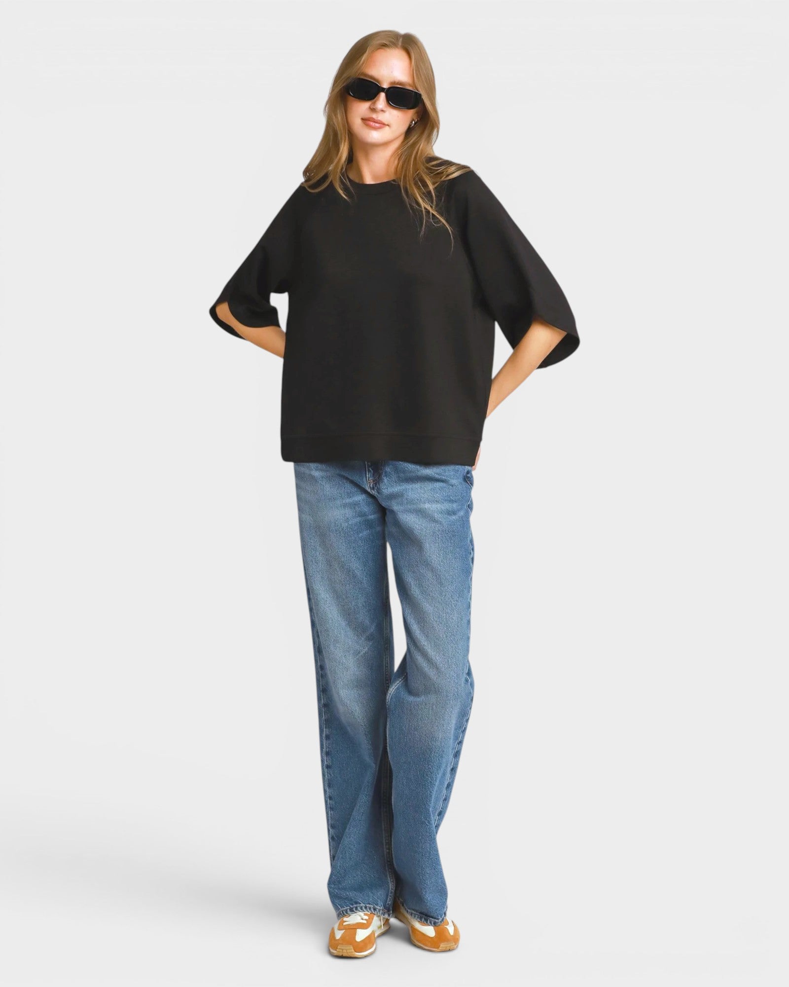 Person wearing a black oversized shirt and blue jeans on a white background