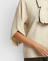 Beige blouse with a black strap over a white background