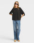 Person wearing a black oversized shirt and blue jeans on a white background