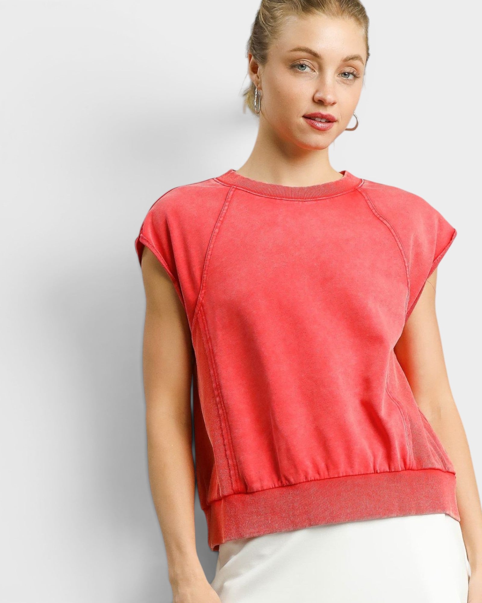 Woman wearing a red sleeveless top against a plain background