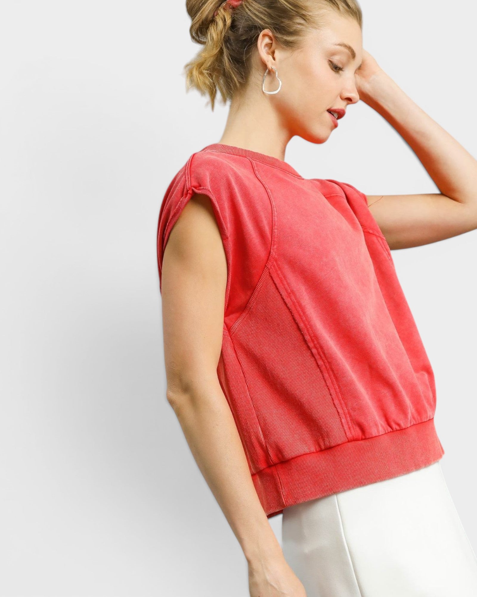 Woman wearing a red sleeveless top against a white background