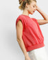 Woman wearing a red sleeveless top against a white background