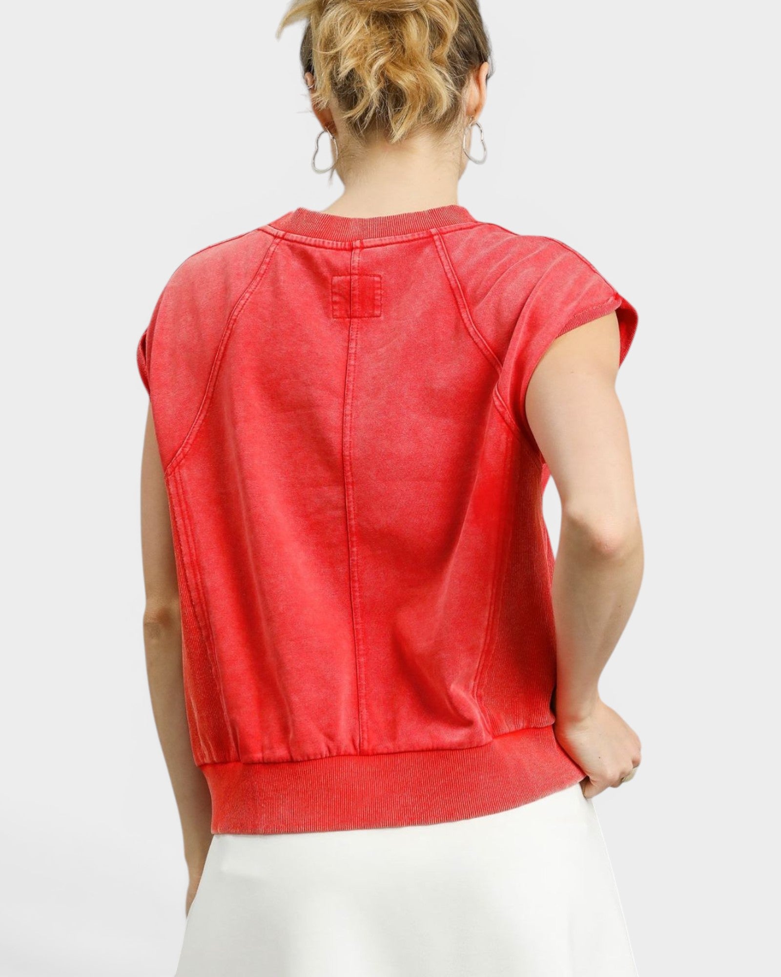 Red sleeveless top worn by a person on a white background