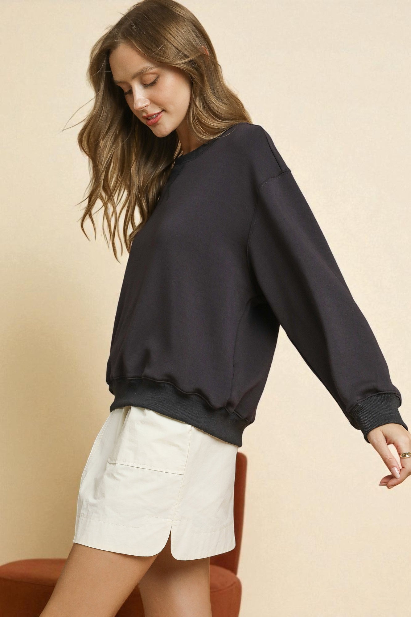 Woman wearing a black sweatshirt and white shorts on a beige background