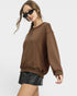 Woman wearing a brown sweatshirt and black leather shorts on a white background