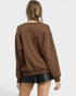 Person wearing a brown sweatshirt and black leather shorts on a white background