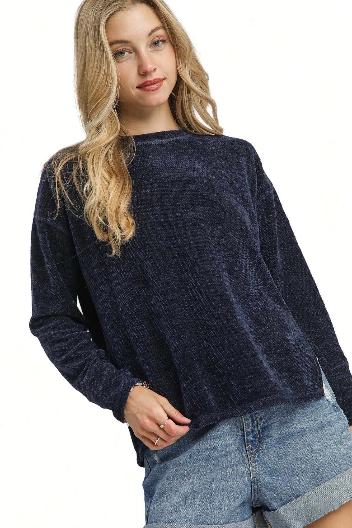 Woman wearing a navy blue sweater and denim shorts on a white background