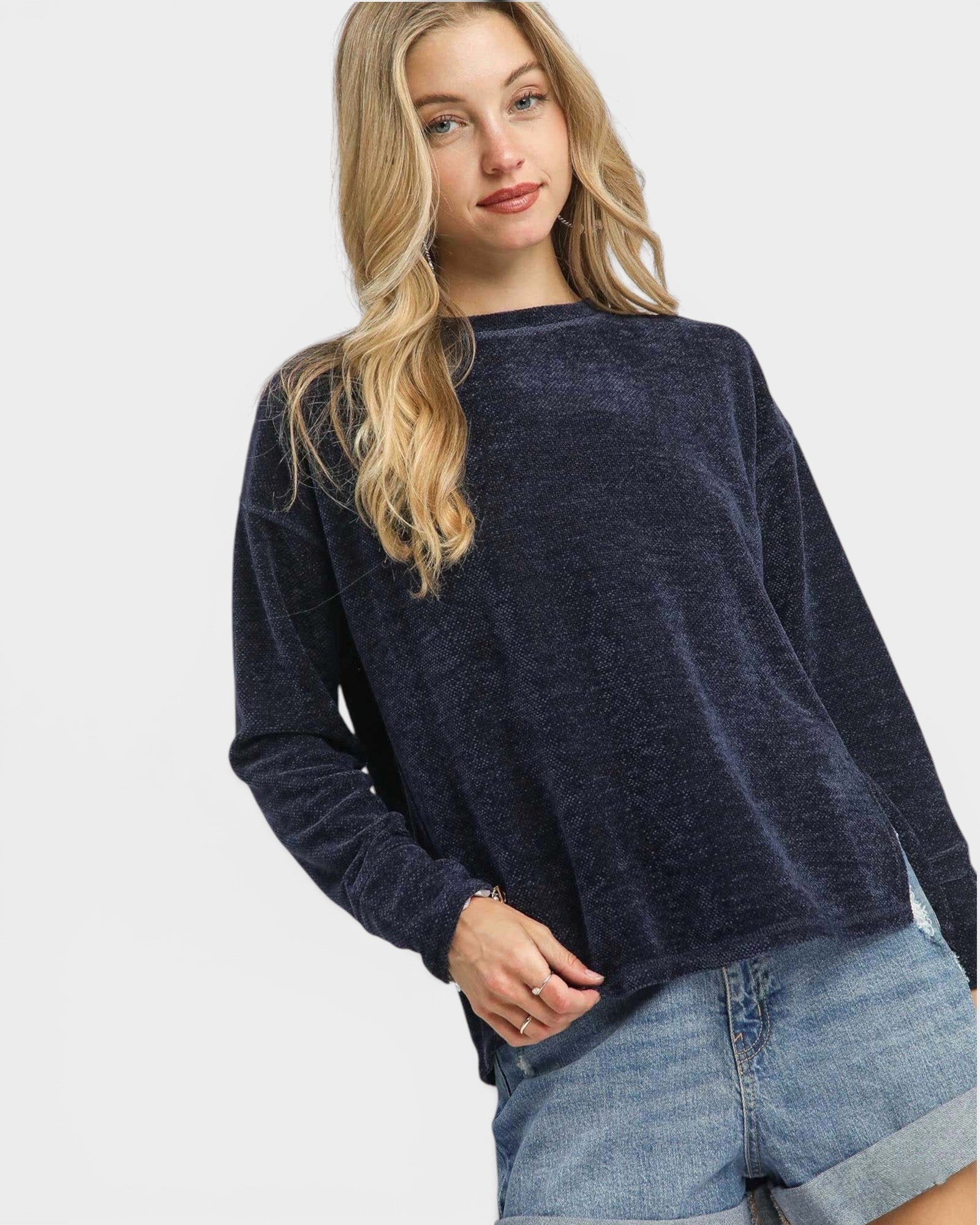 Woman wearing a navy sweater and denim shorts on a white background