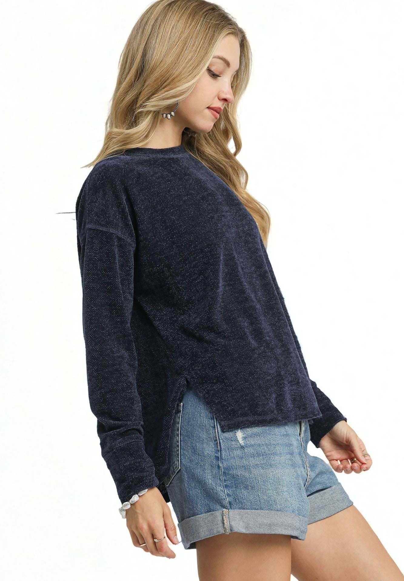 Woman wearing a navy sweater and denim shorts on a white background