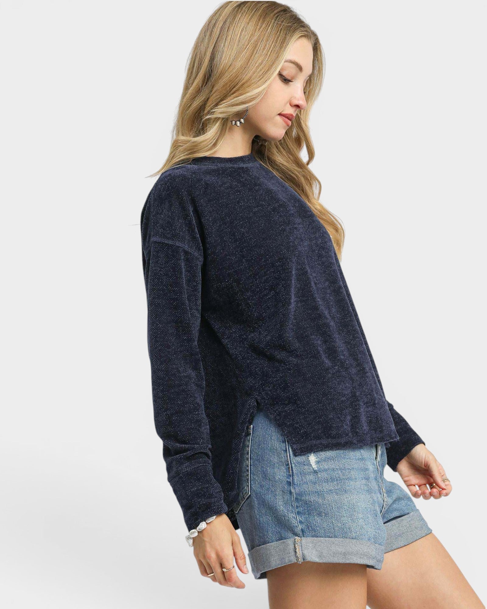 Woman wearing a navy sweater and denim shorts on a white background