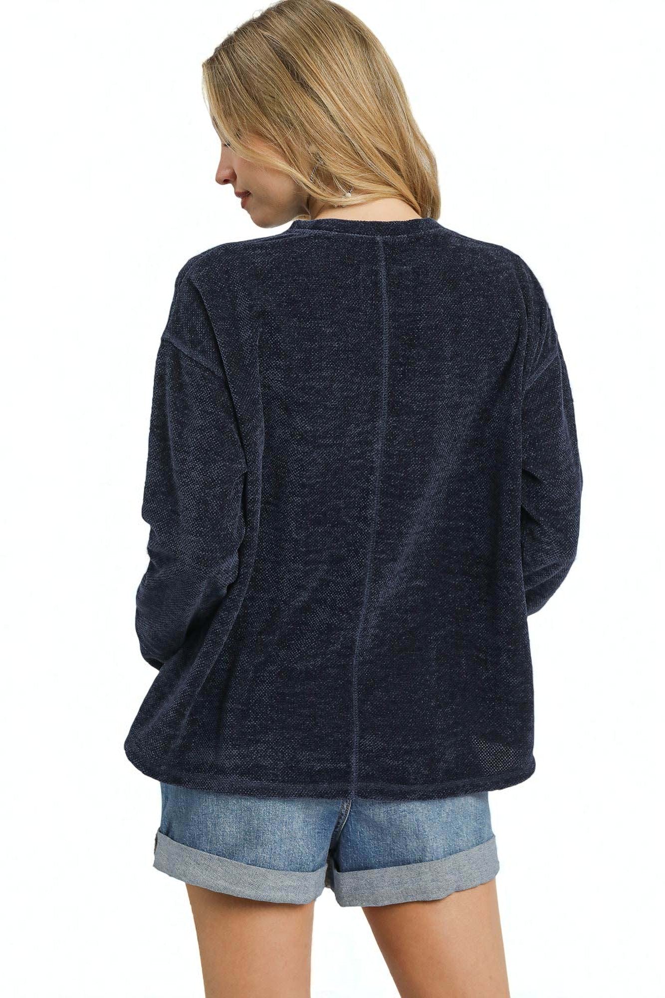 Woman wearing a navy blue chenille top on a white background