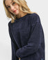 Woman wearing a navy blue sweater on a light gray background
