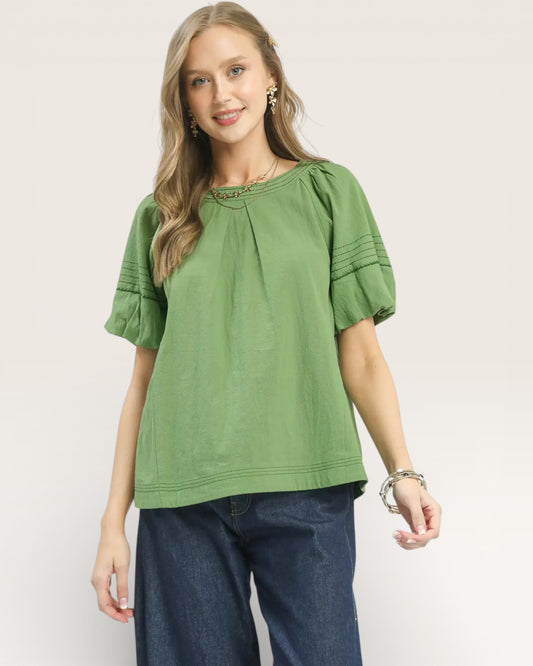 Woman wearing a green blouse with ruffled sleeves on a white background