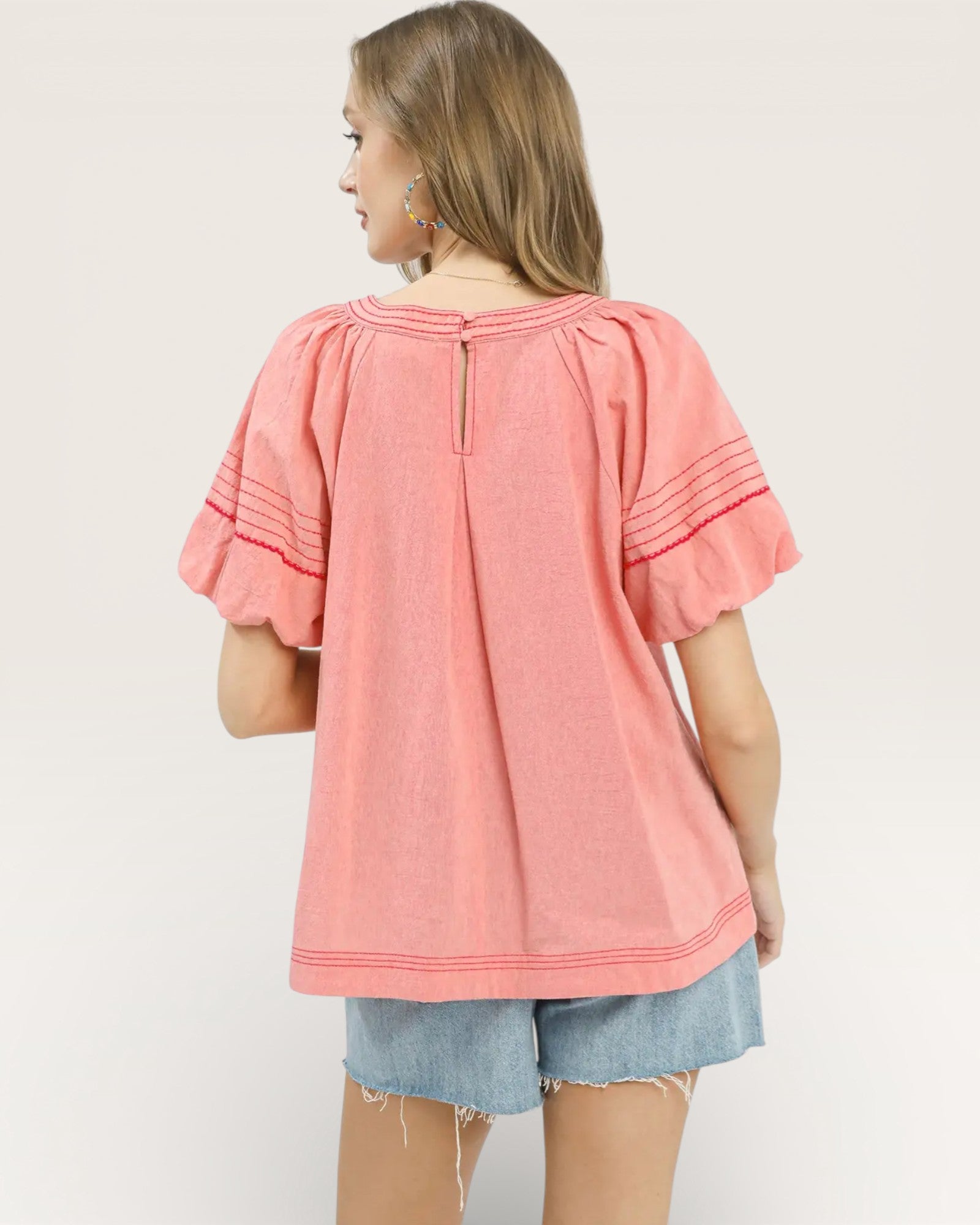 Woman wearing a pink blouse with ruffled sleeves on a white background