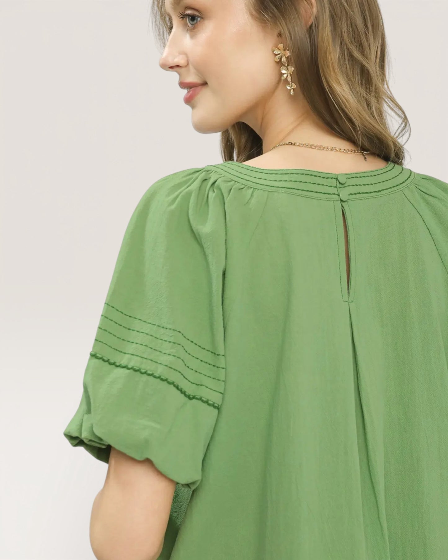 Woman wearing a green blouse with a plain background