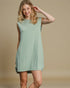 Woman wearing a light green sleeveless dress against a beige background