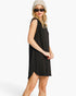 A woman modeling a sleeveless black shift dress with a side slit, styled with a beige knit beanie, black sunglasses, and red lipstick against a plain white background.