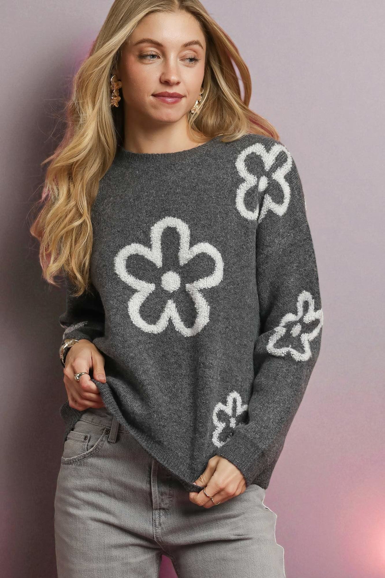 Woman wearing a gray sweater with white flower patterns on a gradient background