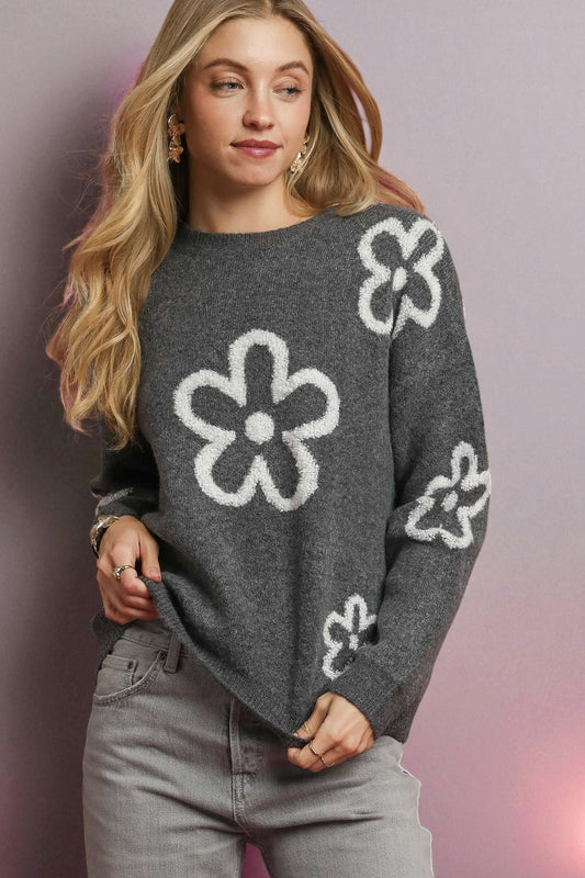 Woman wearing a gray sweater with white flower patterns on a gradient background