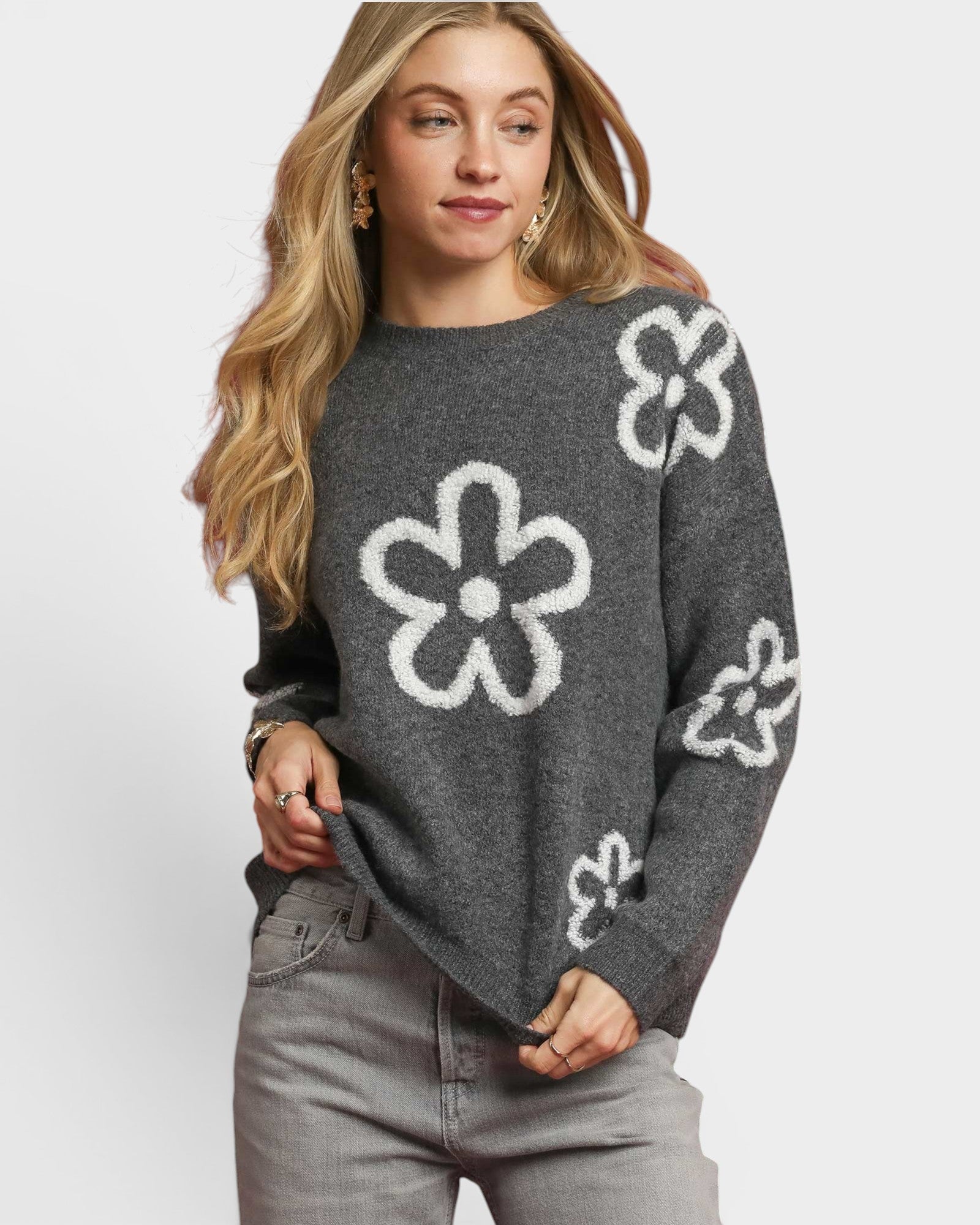 Woman wearing a gray sweater with white floral patterns on a white background