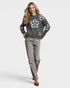 Woman wearing a gray sweater with floral designs and gray pants on a white background