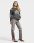 Woman wearing a gray sweater with white floral patterns and gray pants on a light gray background