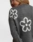 Gray sweater with white flower designs on a plain background