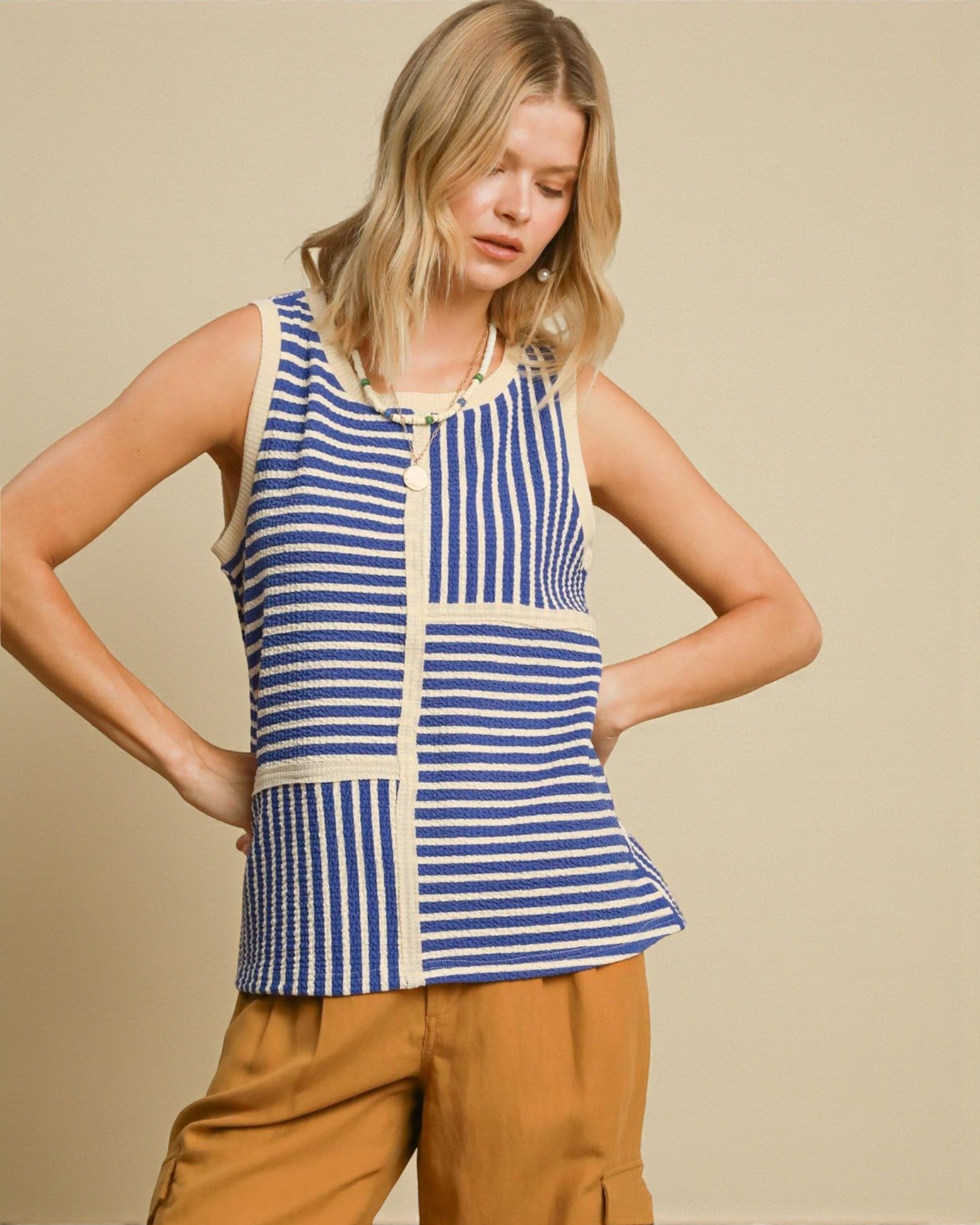 Woman wearing a blue and white striped sleeveless top with beige accents on a beige background
