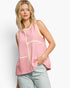 A woman modeling a sleeveless knit top with pink and white vertical stripes and beige trim, paired with light-wash jeans against a plain light gray studio background.