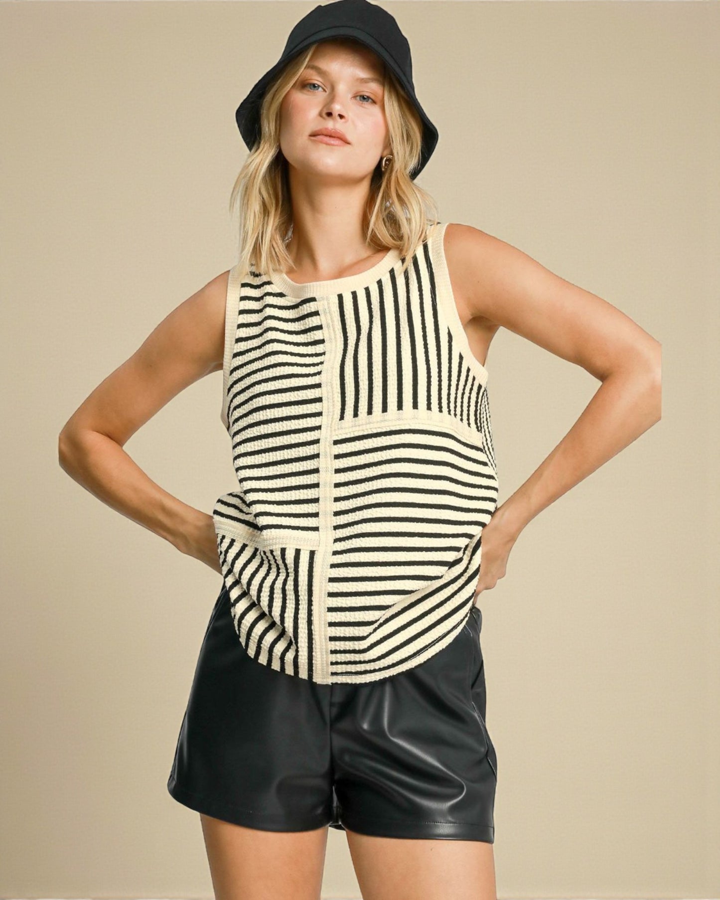 Woman wearing a striped tank top and black shorts with a beige background