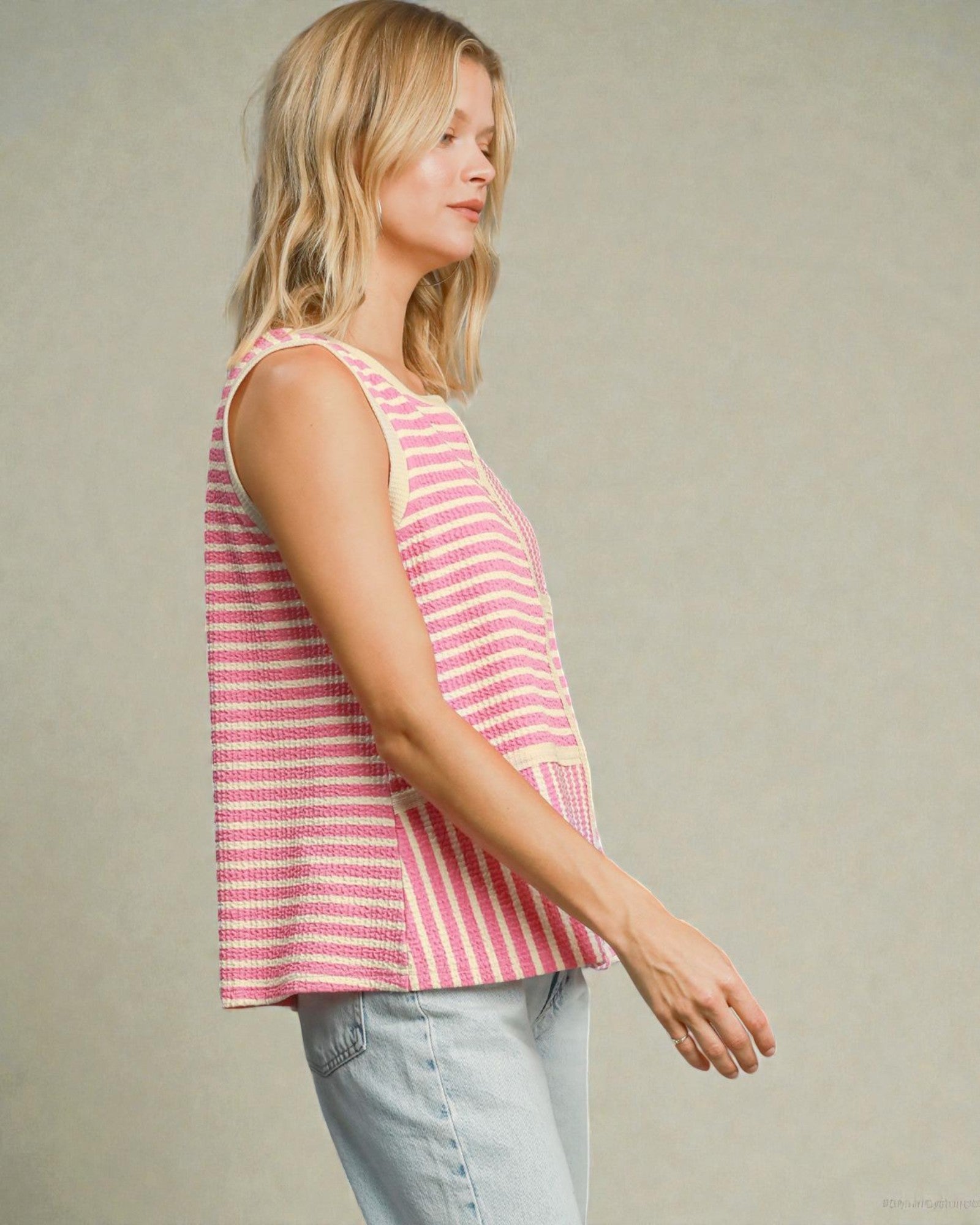 Woman wearing a pink and white striped sleeveless top against a neutral background