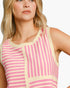A close-up of a woman wearing a sleeveless knit top with vertical pink and cream stripes and a round neckline.
