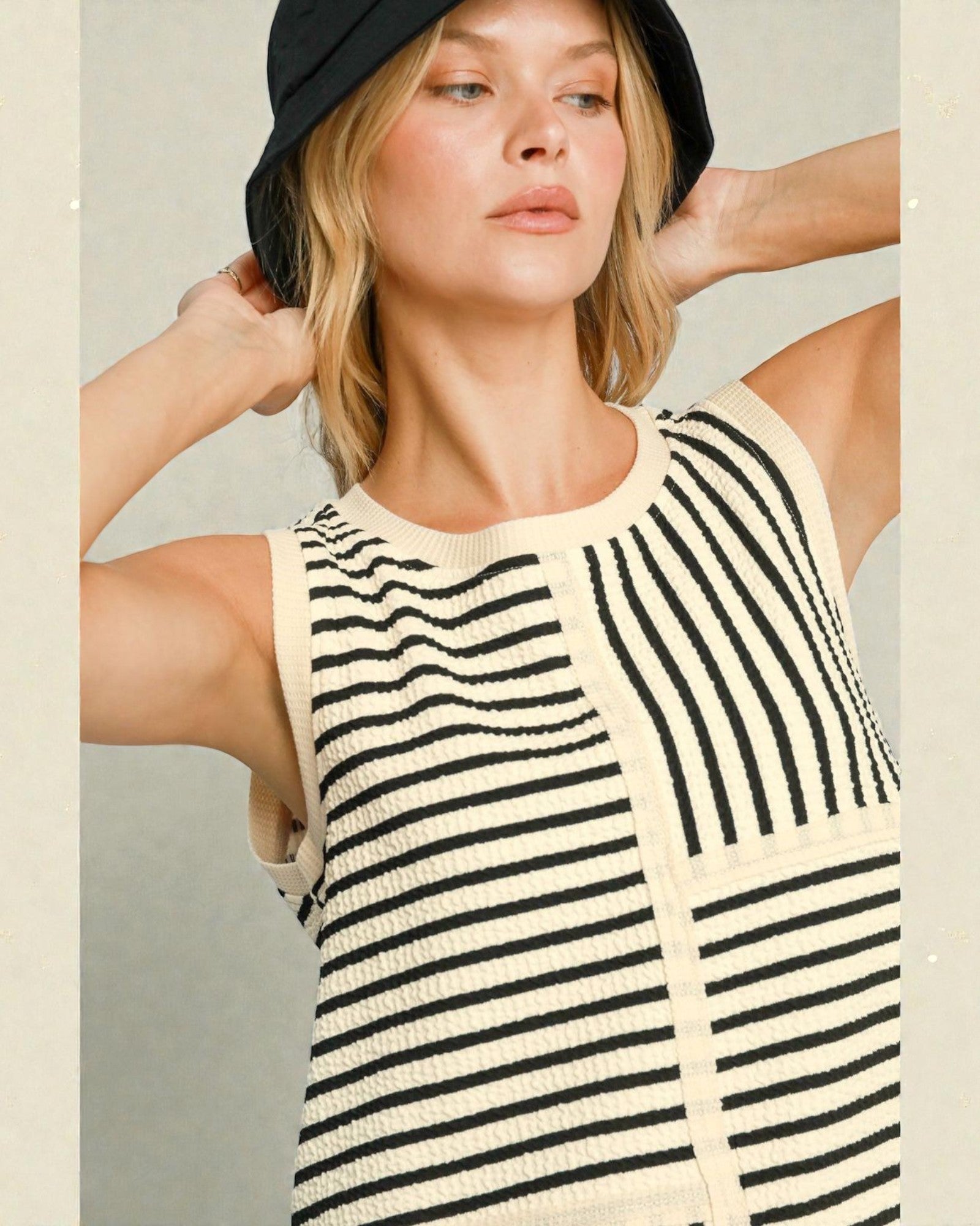 Woman wearing a black and white striped sleeveless top with a neutral background