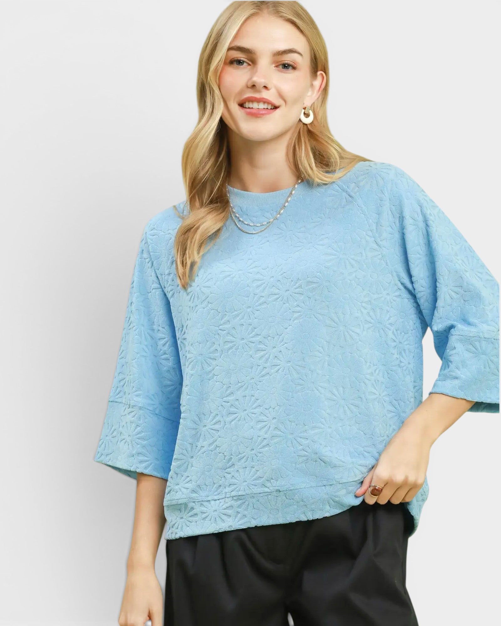 Woman wearing a light blue textured sweater against a plain background