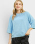 Woman wearing a light blue textured sweater against a plain background