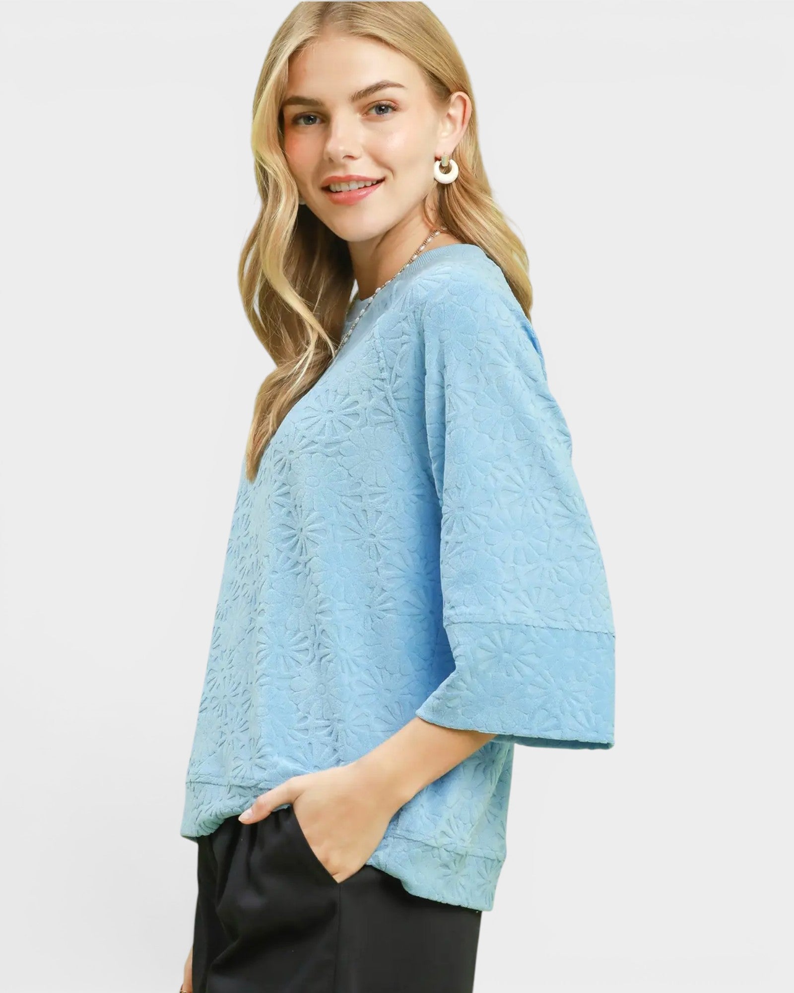 Woman wearing a light blue textured top on a white background